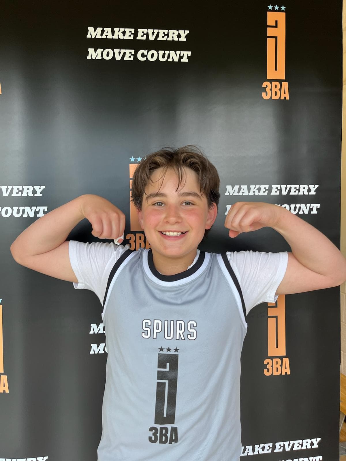 A smiling player flexing in front of the 3BA 'Make Every Move Count' backdrop