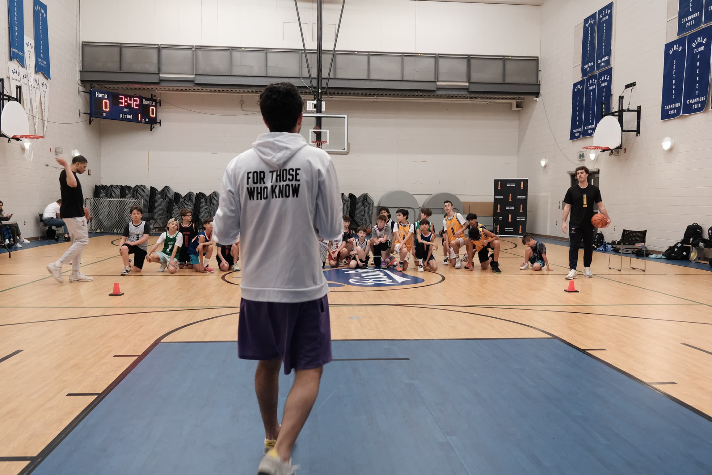 A coach walking toward rows of seated students in a school gym