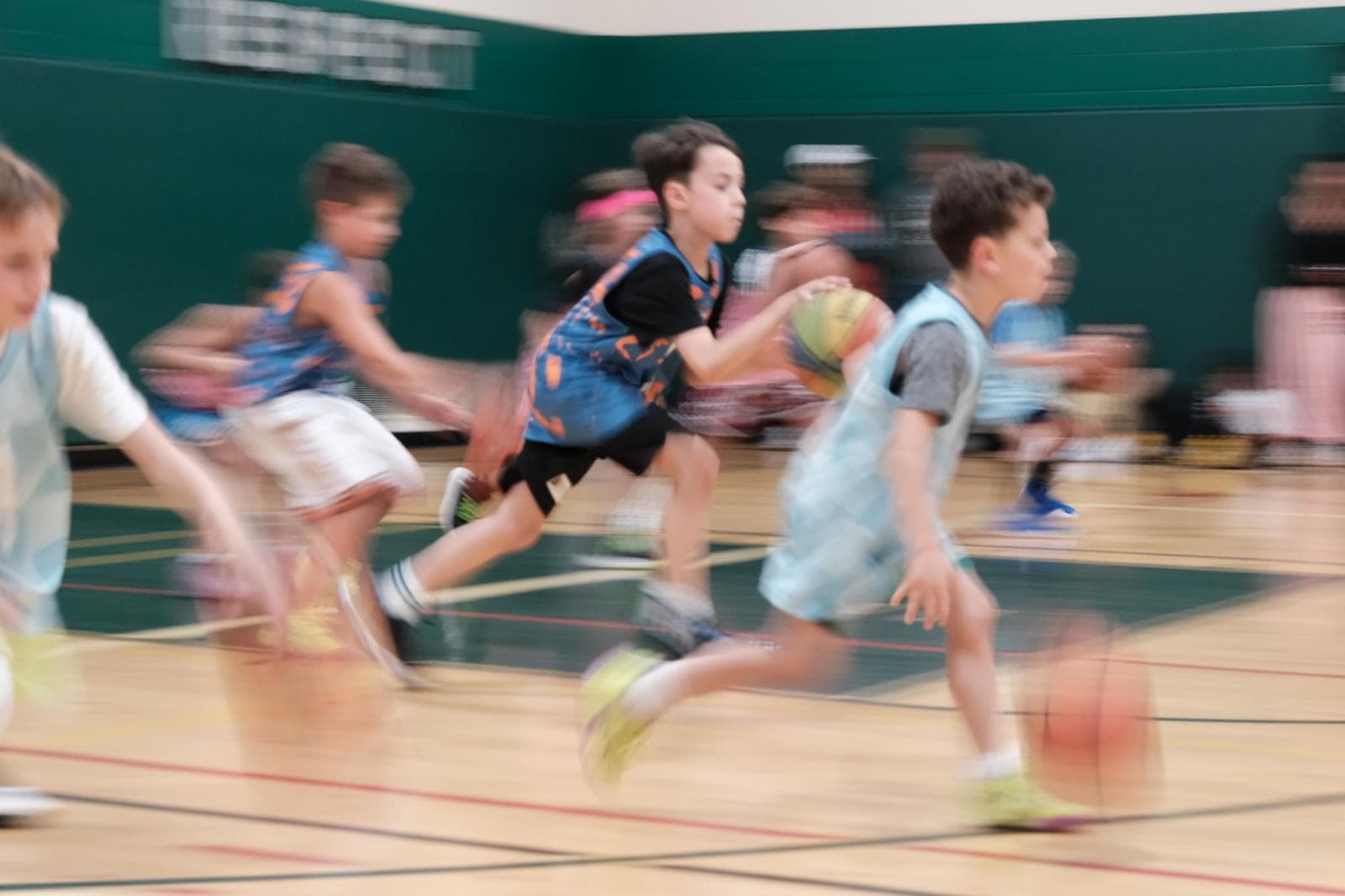 Young players sprinting down the floor with basketballs, full of energy