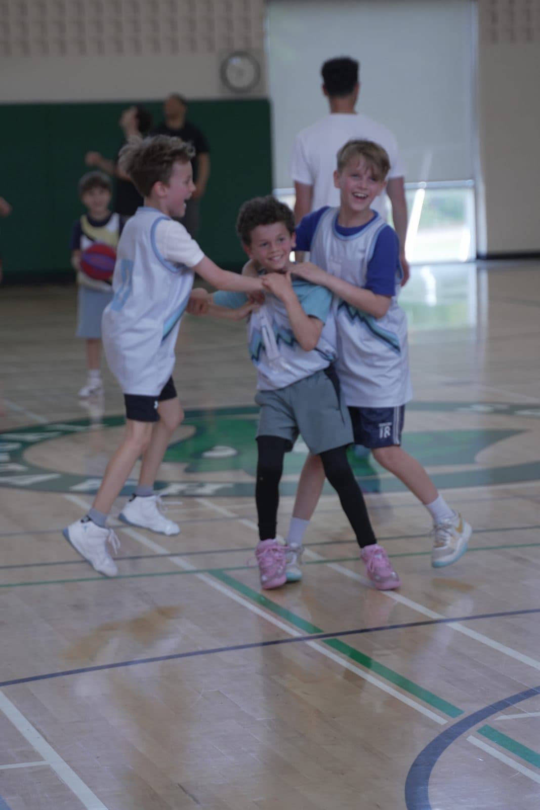Three teammates celebrating together at mid-court
