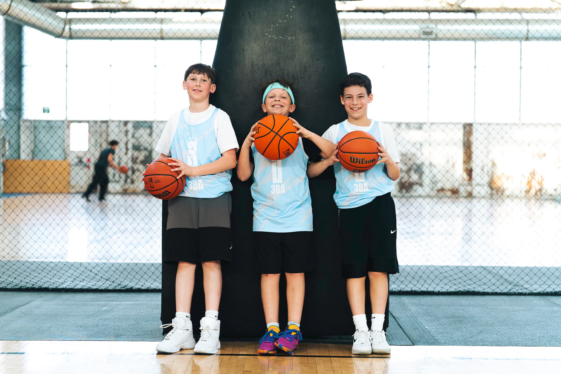 Three Junior division players in light blue 3BA pinnies holding basketballs