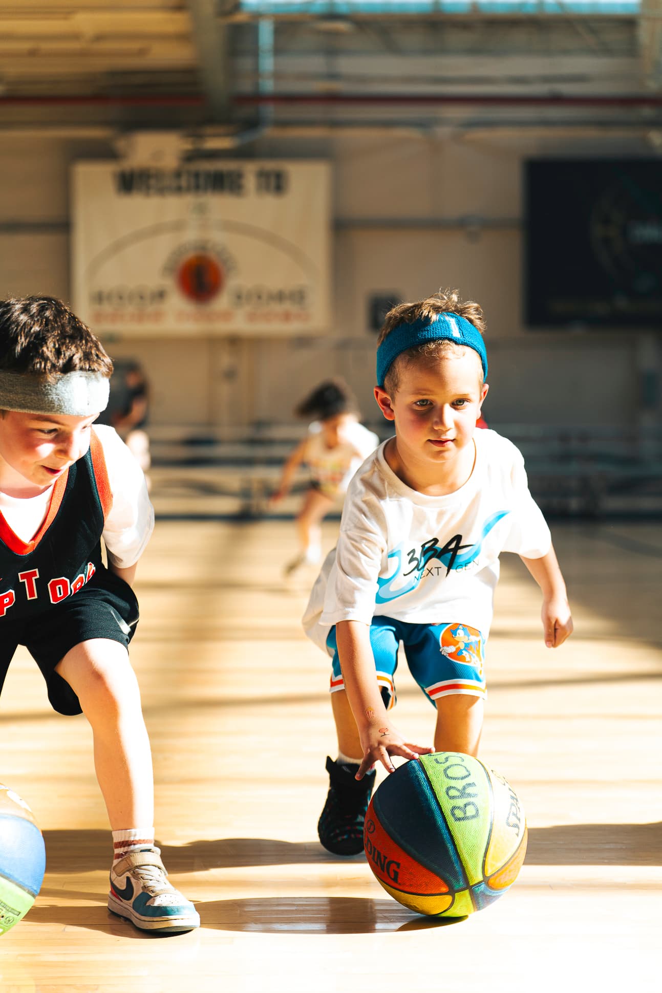 Two Next Gen athletes dribbling low side by side across the gym floor